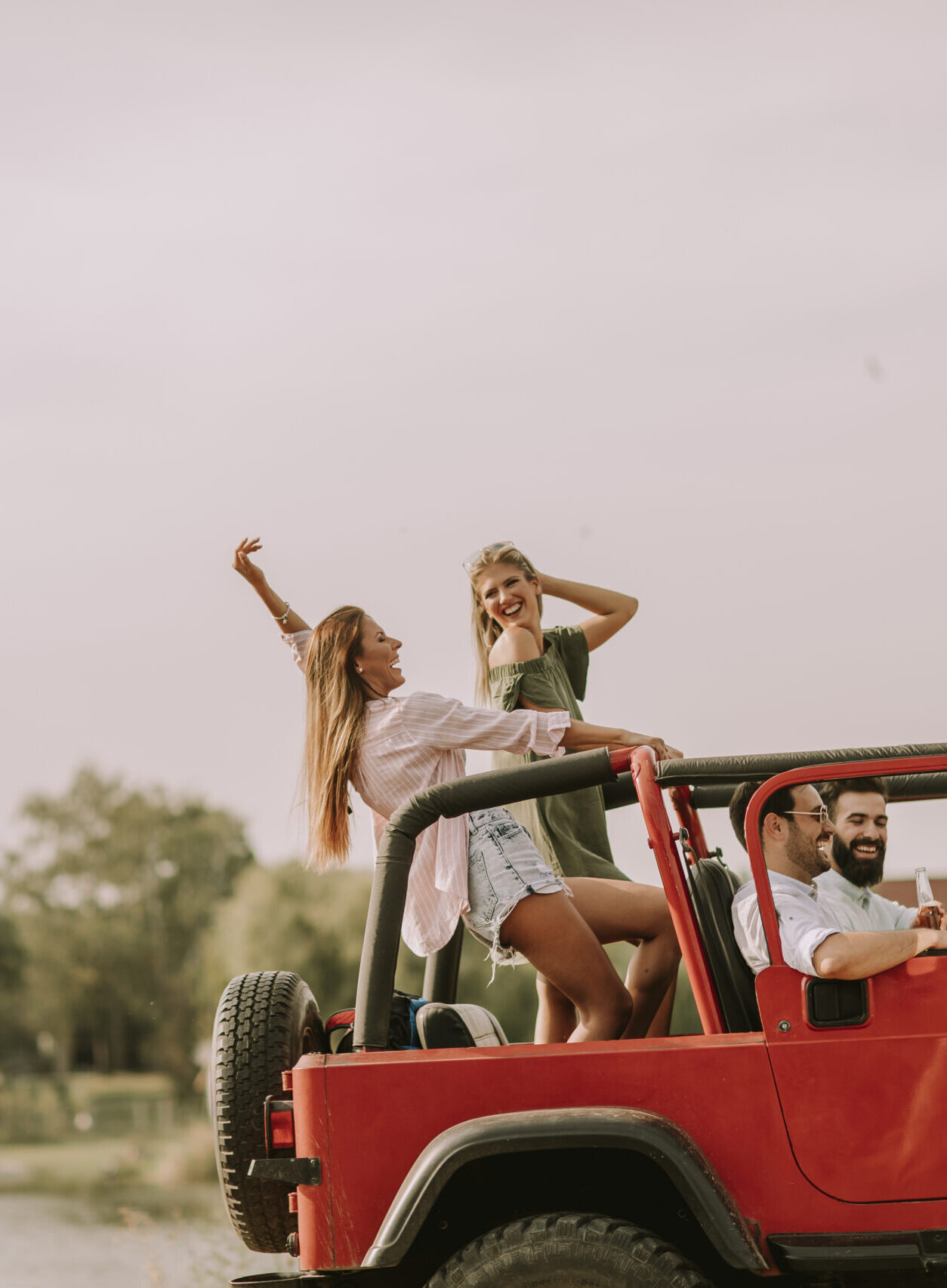 3 young adults having fun in a jeep, drinking while blasting music